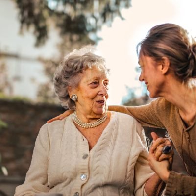 Joyful adult daughter greeting happy surprised senior mother in garden